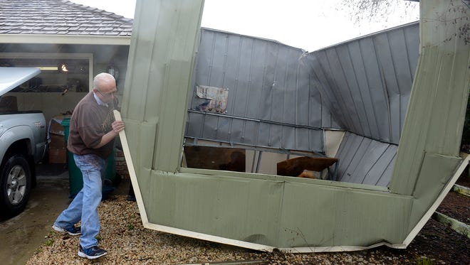 Richard Boles moves a storage shed that was blown from his backyard over his house to his front yard by heavy winds at Las Palmas in rural Salinas, Calif., on Feb. 17, 2017.
