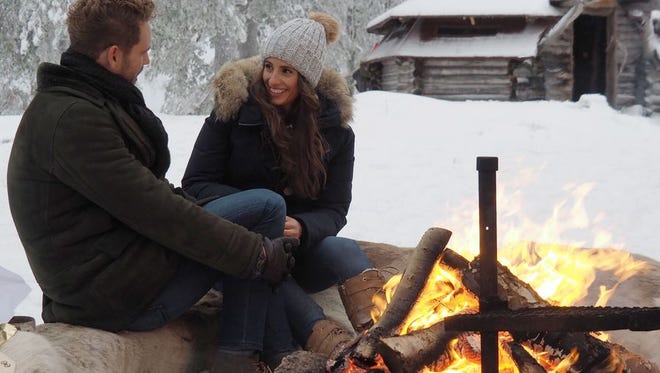 Vanessa and Nick warm by a fire in Finland during their last date in the season finale of "The Bachelor."
