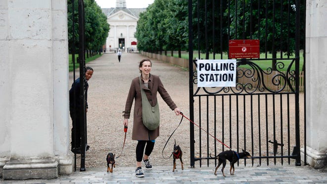 A woman with three dogs leaves the polling station at Burton Court pavilion in southwest London on June 8, 2017, as Britain holds a general election.