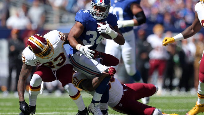 New York Giants running back Shane Vereen (34) carries the ball as Washington Redskins safety DeAngelo Hall (23) and safety David Bruton Jr. (30) defend during the first quarter at MetLife Stadium.
