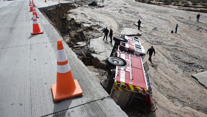 Officials look over the scene where a San Bernardino County Fire Department fire engine fell Friday from southbound Interstate 15 where part of the freeway collapsed due to heavy rain in the Cajon Pass, Calif., on Feb. 18, 2017.