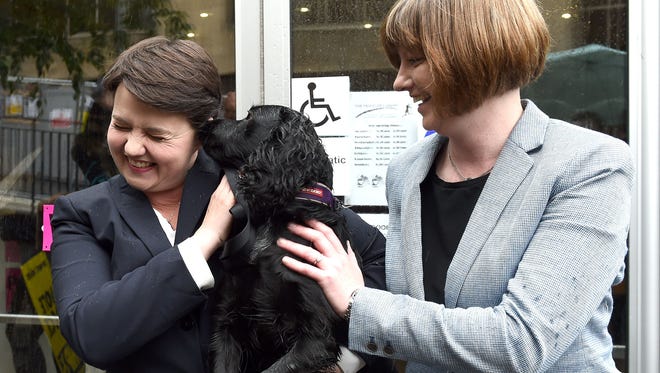 Scottish Conservative leader, Ruth Davidson, left, and her partner Jen Wilson and their dog Mister Wilson, at a cafe set up as a polling station, in Edinburgh, Scotland.