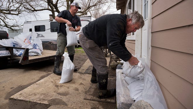 Bill Bernstein and his son Will, lay sandbags around at the door of his home as they prepare for another storm on Feb. 19, 2017, in Maxwell, Calif. The first outer rain bands from a powerful Pacific storm headed to Northern California on Sunday brought light rain and wind and renewed warnings of possible flooding in the already soggy region.