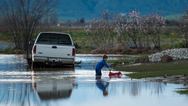 Barr Torrens, 5, plays in flooded neighborhood streets after a deluge of rain and water-runoff flooded much of Maxwell, Calif., Saturday, Feb. 18, 2017. Northwest of Sacramento, several hundred people were evacuated Saturday as overflowing creeks turned the town of Maxwell into a brown pond, with some homes getting 2 feet of water.