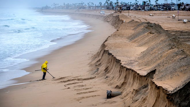 Stan Ross of Newport Beach digs up some sand near the Balboa Pier in Newport Beach, Calif., on Feb. 18, 2017, as he looks for coins and jewelry following Friday's storm that eroded the beach, brought high winds, and heavy rain which flooded many areas in Southern California.