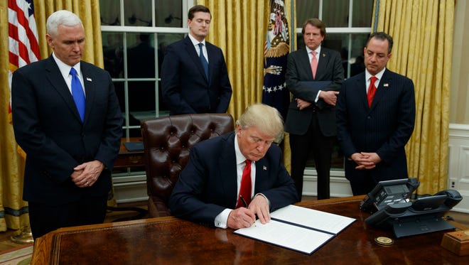 President Trump, flanked by Vice President Pence and chief of staff Reince Priebus, signs an executive order on health care on Friday.
