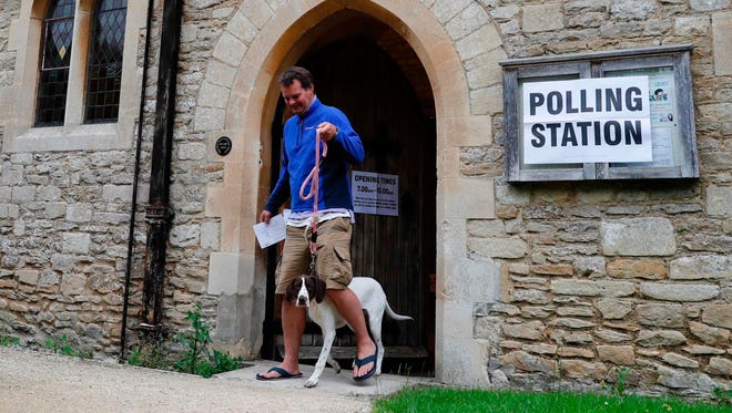 A man with a dog leaves a church set up as a polling station in Stadhampton, near Oxford, west of London.