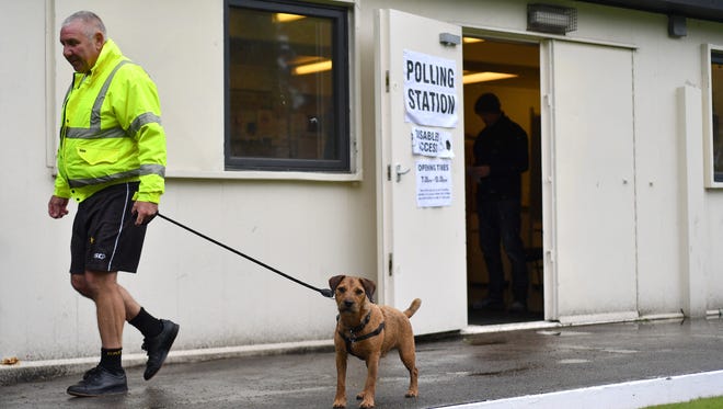 A man leaves with his dog after voting at a polling station at Royton Park Bowling Club in Royton.