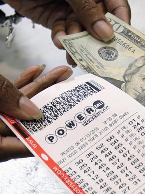 A clerk hands over a Powerball ticket for cash Jan. 13, 2016, at Tower City Lottery Stop in Cleveland.