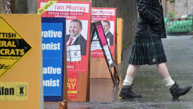 A voter passes signs for local candidates in Edinburgh, Scotland.