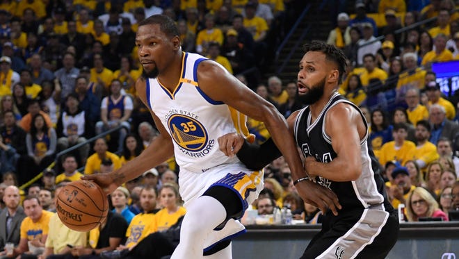 Golden State Warriors forward Kevin Durant dribbles the basketball against San Antonio Spurs guard Patty Mills during the first quarter in Game 2 of the Western Conference finals.