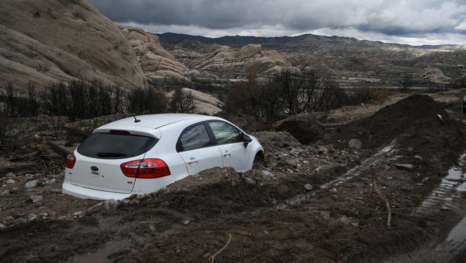 An abandoned Kia sedan is seen stuck in heavy mud in Lone Pine Canyon Road near Highway 138 in Phelan, Calif., on Feb., 18, 2017.