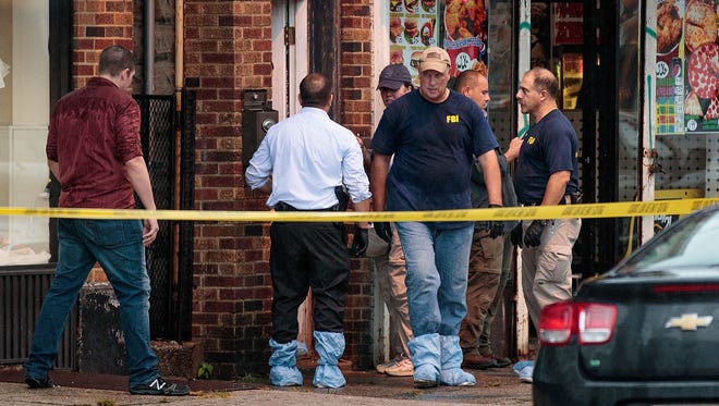 Law enforcement officials investigate an Elizabeth, N.J.,  residence in connection with a string of bombings in the New York City area.