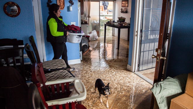 A member of the Barazza family removes belongings to an upstairs apartment after  flood waters overtook their neighborhood in San Jose, Calif. Feb. 22, 2017.