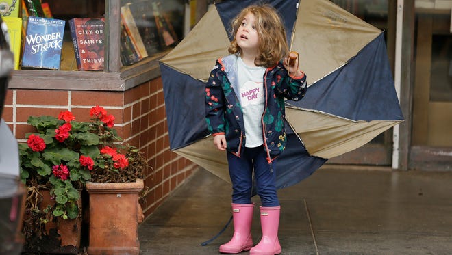 Three-year-old Emerson Cassidy takes cover from the rain in a storefront entryway on Feb. 20, 2017, in San Anselmo, Calif.