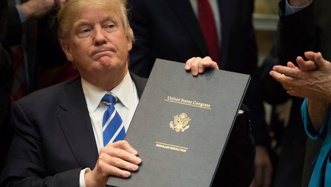 President Trump holds up one of four bills he signed Monday in the Roosevelt Room of the White House.