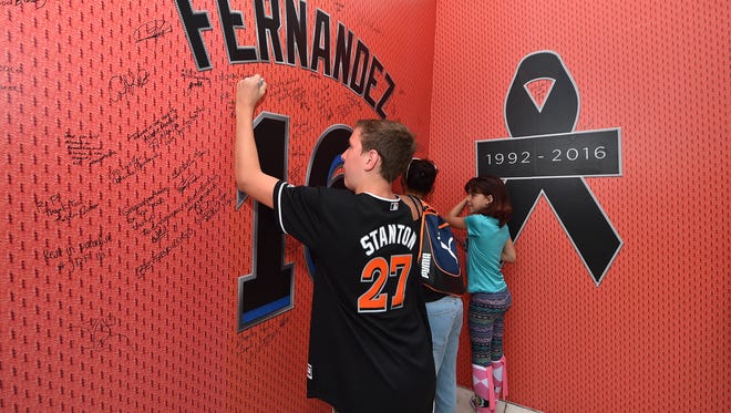A young fan signs a wall placed outside a gate at Marlins Park in honor Jose Fernandez.