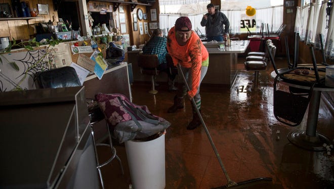 Tina Dry mops up water and mud that seeped into her family diner, Kim's County & Cafe, after area storms brought flood-level water to the Colusa County town of Maxwell, Calif. on Feb. 18, 2017.