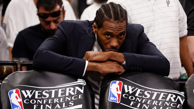 San Antonio Spurs small forward Kawhi Leonard (in suit) watches from the bench against the Golden State Warriors during the first half in game three of the Western conference finals of the NBA Playoffs at AT&T Center.