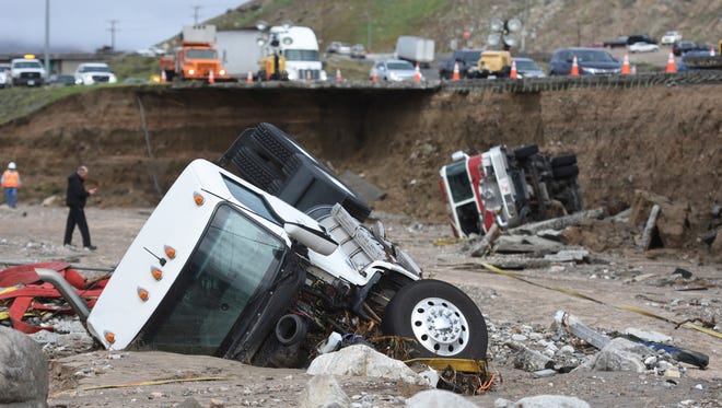Officials look over the scene on Feb. 18, 2017,  where  a tractor trailer fell Friday from southbound Interstate 15 where part of the freeway collapsed due to heavy rain in the Cajon Pass, Calif.