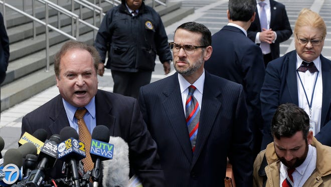 David Wildstein, center, listens to his attorney Alan Zegas, center right at podium address the media as they leave federal court after a hearing Friday, May 1, 2015, in Newark, N.J. Wildstein, a former ally of Gov. Chris Christie pleaded guilty Friday to helping engineer traffic jams at the George Washington Bridge in a political payback scheme he said also involved two other Christie loyalists. But he did not publicly implicate Christie himself. (AP Photo/Mel Evans)