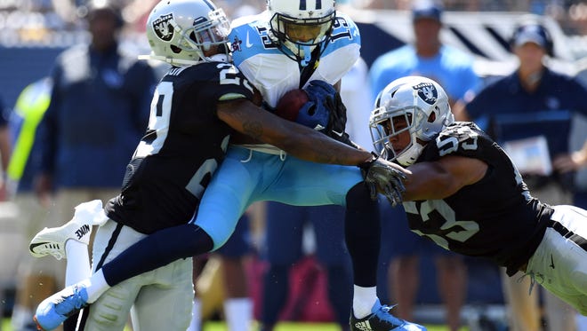 Tennessee Titans receiver Rishard Matthews (18) catches the ball between coverage by Oakland Raiders cornerback David Amerson (29) and linebacker Malcolm Smith (53) during the first half at Nissan Stadium.