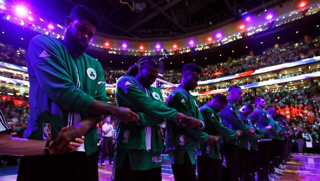 Celtics forward Amir Johnson joins hands in unity with his teammates during the national anthem.