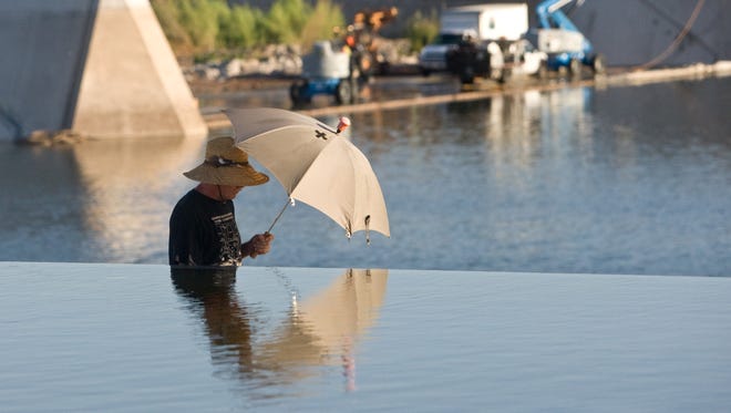 Matt Thomas uses an umbrella to shield himself from the morning sun while going for a walk next to the Tempe Town Lake in 2010.