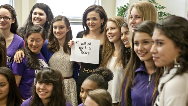 Facebook exec Sheryl Sandberg poses for a photo with students at Sequoia High School.  The sign she holds is a message of empowerment that answers the question "What would you do if you were't afraid?'